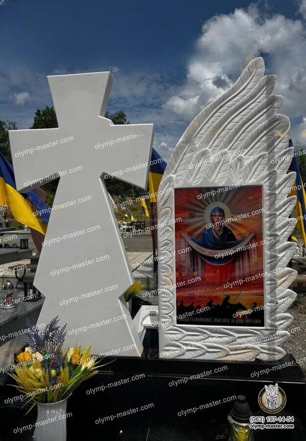 Обратная сторона белого памятника военному с резным крылом ангела, казацким крестом и иконой Покрова Пресвятой Богородицы.