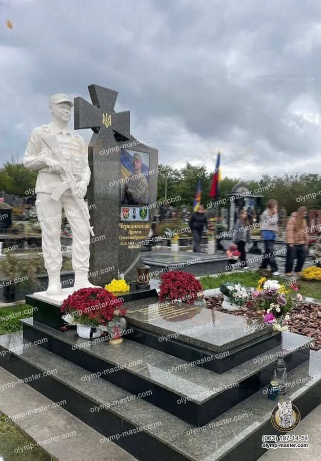 Общий вид установленного военного мемориала с казацким крестом, белой скульптурой воина и гранитной надгробной плитой на кладбище.
